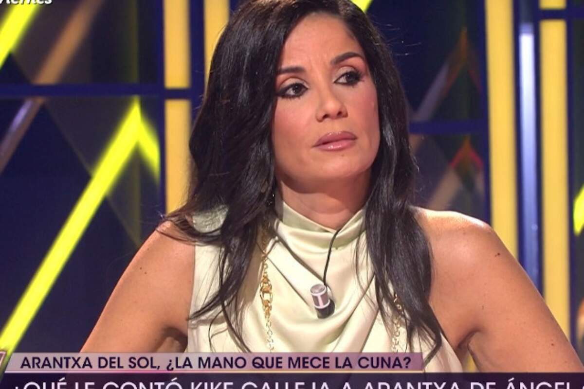 Foto de Ana Herminia en un plató de televisión hablando con cara seria y mirando de lado usando el cabello suelto y largo con una blusa blanca